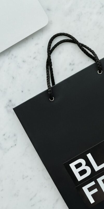Stylish Black Friday shopping bag and laptop on a sleek marble surface.