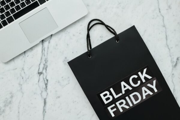 Stylish Black Friday shopping bag and laptop on a sleek marble surface.